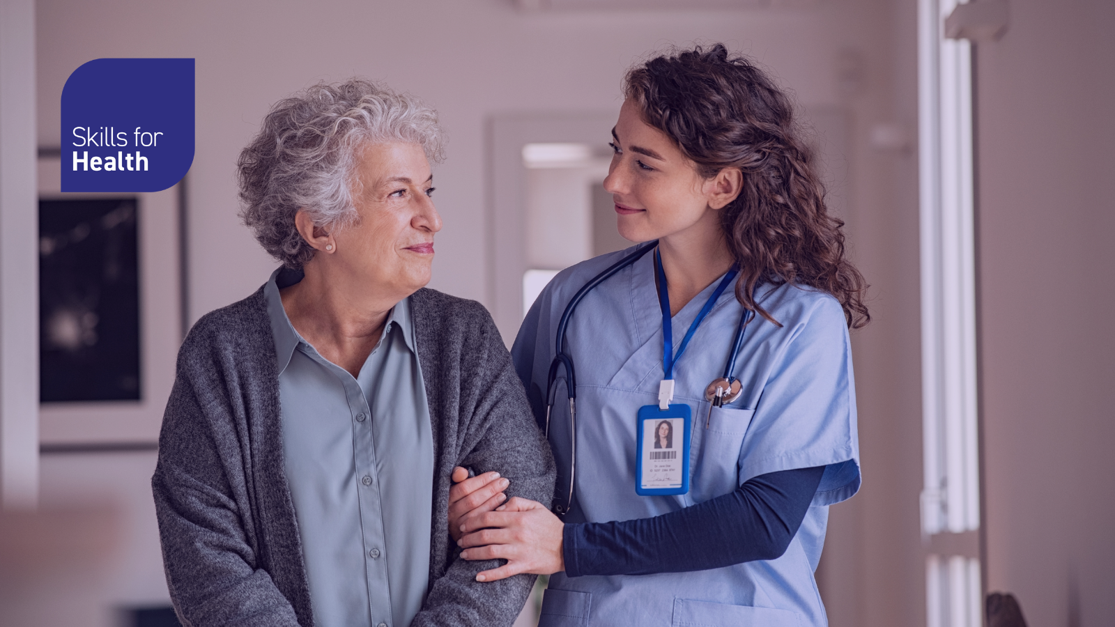 A younger nurse and older patient walking arm in arm smiling