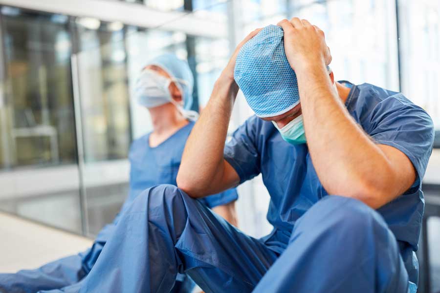 Doctcr sat on floor in Mask holding head in hands